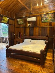 吉仙猫田河度假村的卧室配有一张床铺,位于带木墙的房间内