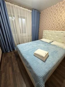 Prigorodnyy5 мин международный аэропорт的一间卧室配有一张带蓝色窗帘的床和一扇窗户