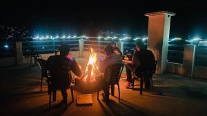 马拉里Hotel The Meadows Open Terrace Bonfire的一群人晚上坐在火坑周围