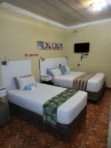 比勒陀利亚At Blackwood Guesthouse的酒店客房设有两张床和一台平面电视。