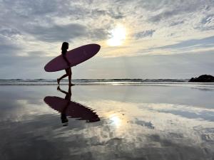 KannouraHotel NALU　ホテルナル的一名妇女带着冲浪板在海滩上行走