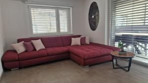 拉什科Apartmaji PR' KERIN的客厅里一张红色的沙发,配有桌子