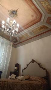 比萨Relais Corso Storico的一间卧室设有天花板、吊灯和一张床
