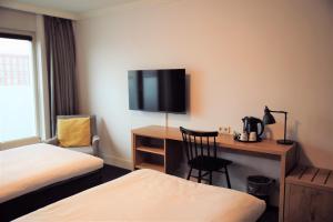 布雷达凯泽布雷达中心金郁金香酒店的酒店客房设有一张桌子和一台墙上的电视。