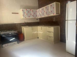 Madain Salehاستراحات ومخيم يمك دروبي的厨房配有白色橱柜和黑色冰箱。