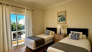 维拉摩拉Ellegance by Check-in Portugal的一间卧室设有两张床,窗户设有阳台