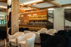 波罗维茨"Park Hotel Ela"的一间设有白色椅子的餐厅和一间酒吧