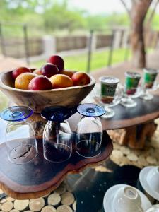侯斯普瑞特Wild Dog Guest Lodge的桌子,上面放着一碗苹果和一碗玻璃杯
