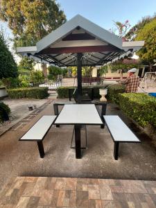 Ban Tao ThanSuanpai Resort Sattahip的一张带两个长椅和一把雨伞的野餐桌