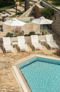 蒂锡利维Erietta Aparthotel的一个带椅子和遮阳伞的游泳池和一个游泳池