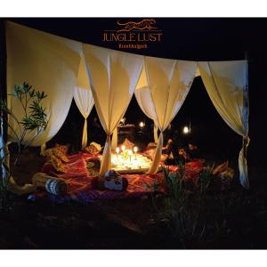 贡珀尔格尔The Jungle Lust的一群人坐在帐篷里,围着火堆