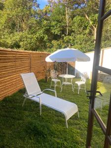 卢米亚Matha Pousada e Bistrô的院子里设有两把椅子和一张桌子及一把遮阳伞