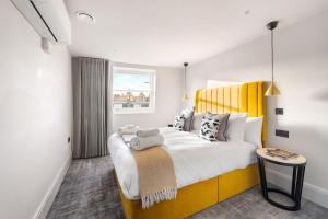 伦敦Kentish Town Road的一间卧室配有一张带黄色床头板的大床