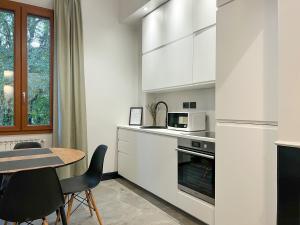 博洛尼亚Mondo7的厨房配有白色橱柜和桌椅