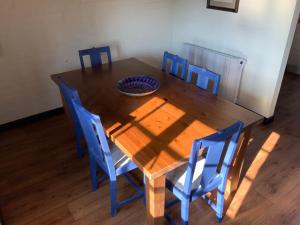 锡德茅斯Cider Cottage - 3 Bedroom - Onsite Parking的一张带蓝色椅子的木桌和一个碗