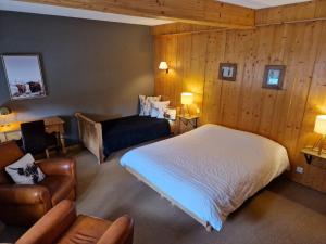 莱鲁斯Lodge Hotel Les Rousses的一间卧室配有一张床、一张沙发和一把椅子