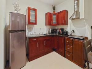 利比里亚Apartment Equipped With Excellent Location的厨房配有木制橱柜和不锈钢冰箱。