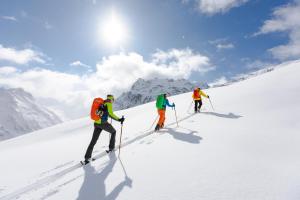 施伦斯玛利德小木屋的三人在雪覆盖的山上越野滑雪
