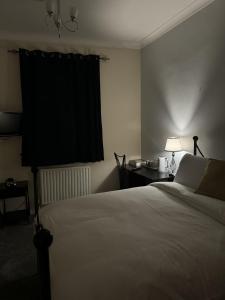 彻特西Windsor Wine and Dine的一间卧室配有一张床和一张带台灯的桌子