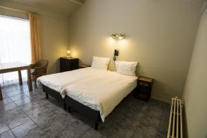 WeeldeHotel Pacific的一间卧室配有一张带白色床单和桌子的大床