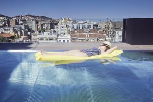 巴塞罗那The Onsider - Luxury 4 Bedroom Apartment的女人在游泳池里躺在木筏上