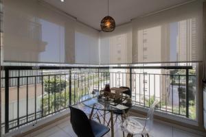 瓜鲁柳斯Apartamento 408 em condomínio de alto padrão的客房设有带玻璃桌和椅子的阳台。