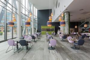 米兰voco Milan-Fiere, an IHG Hotel的餐厅设有紫色椅子、桌子和窗户