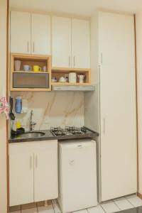 巴西利亚Studio Sudoeste Brasília的厨房配有白色橱柜、水槽和微波炉