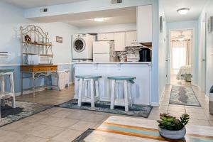 海洋岛海滩The Turquoise Pearl的厨房配有白色橱柜和凳子