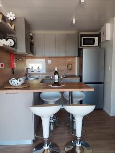 沃迪切Julija Mobile Lux的厨房配有白色凳子和1个带1瓶葡萄酒的吧台