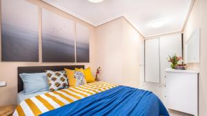 托雷维耶哈Apartamento a 3 min de la playa的一间卧室配有蓝色和黄色枕头的床