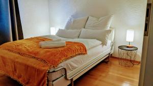 罗斯多夫Ruhige, moderne Wohnung bei Darmstadt in Roßdorf的白色的床、白色枕头和橙色毯子