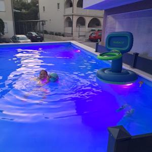 巴什卡沃达Apartments Vila Adrijana & Fitness Studio WOLF BV的一名小孩在游泳池游泳,游泳池里备有水玩具