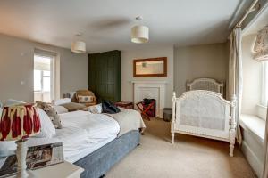 伍德斯托克家庭农场度假屋的卧室配有白色的床和椅子