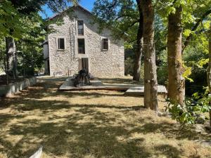 弗米盖赫Villa du Parc le Sapin的一座古老的石头房子,前面有树木