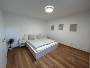 格蒙登Ferienwohnung Gmunden City的一间铺有木地板的白色卧室,配有一张床