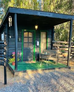 阿尔加罗沃El Bosque Lodge的小屋设有绿门和桌子