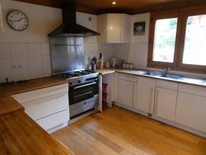 沙泰勒Chalet La piste du Linga的厨房配有白色橱柜和炉灶烤箱。