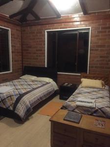 奥塔瓦洛Cabaña Don Pacho的一间卧室设有两张床、一张桌子和一个窗口