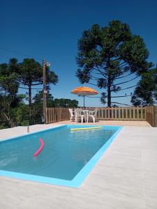 南卡希亚斯Casa aconchegante em meio a natureza的一个带遮阳伞和桌椅的游泳池