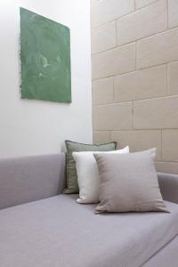 莱切Oronti Accommodations的一张沙发,上面有两张枕头,坐在绿色的画作下