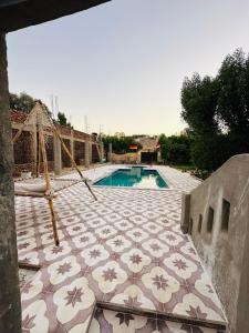 卢克索West Bank luxury villa的游泳池旁设有带吊床的瓷砖天井。
