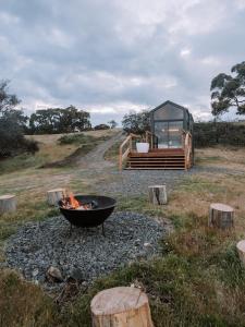 Hilltop Off Grid Tiny House with Outdoor Bath的火坑和田野上的玻璃房子