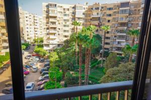 开罗Spacious flat 7 mins to Airport的阳台享有棕榈树停车场的景致。