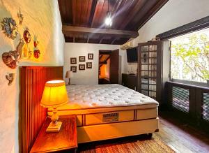 瓜拉雷马Sitio Del Serrans c lazer completo em Guararema SP的一间卧室配有一张床和一张桌子上的台灯