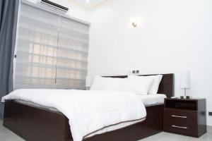 科托努Luxueux Appartement meublé à Cotonou的一间卧室配有一张带白色床单的床和一扇窗户。