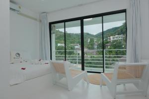 Ka RornMoonE的白色的客房设有床、椅子和大窗户