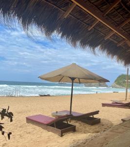 兹波利特Posada Mexico的海滩上设有两把躺椅和一把遮阳伞