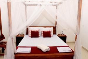 锡吉里亚Green Hut Hotel & Restaurant的卧室配有带红色和白色枕头的天蓬床