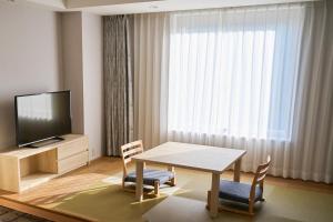 成田成田东武机场酒店的客厅配有桌椅和电视。
